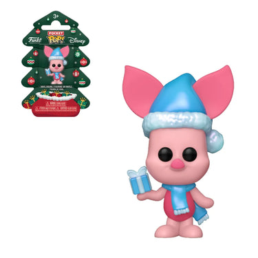 Pink toy figure with blue hat and scarf holding a gift, with packaging in the background