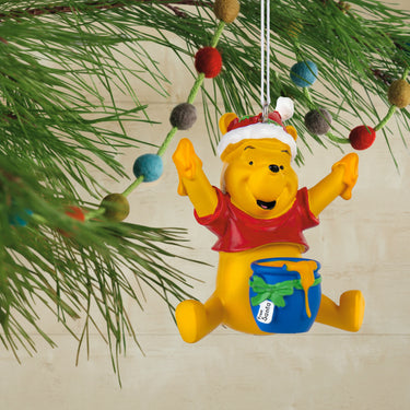 Colorful Winnie the Pooh Christmas ornament on a tree branch.