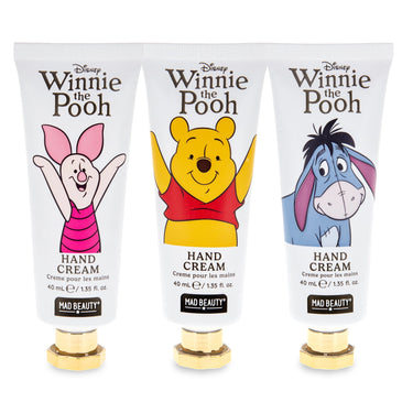 Three white tubes of Disney Winnie the Pooh hand cream lined up side by side, featuring Piglet, Winnie the Pooh, and Eeyore on the front, with gold caps and Mad Beauty branding at the bottom.
