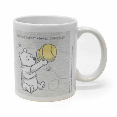 A white ceramic mug with an illustration of Winnie the Pooh holding a ball, and the text 'Feeling rather 11 O'clockish!' above it.
