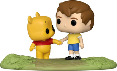 Two figurines, one yellow bear and one boy with brown hair, shaking hands on a green base.