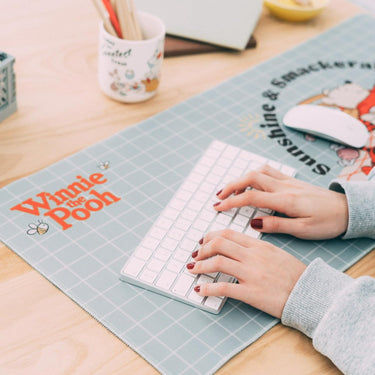 Person using a small keyboard on a desk with a 'Winnie the Pooh' placemat.