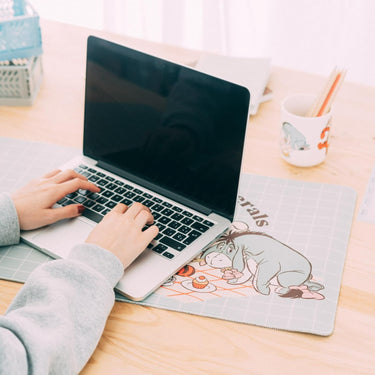 Person using a laptop on a desk with a mouse pad
