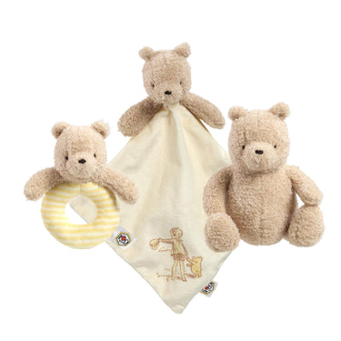 Set of three teddy bears with a comfort blanket and rattle on a white background