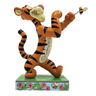 A figurine of Tigger from Winnie the Pooh, holding a baseball bat and fighting a bee, with orange and black coloring and rosemaling details.