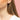 Close-up of an ear with a diamond earring against a pink background