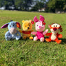 Four Winnie the Pooh plush toys on grass with a blurred background