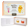 Mad Beauty Disney Winnie the Pooh Lip Balm Collection shown in its outer packaging and opened to reveal two small lip balm jars labeled 'HUNNY' inside a wooden tray.