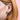 Close-up of an ear wearing a small silver Winnie the Pooh stud earring with a pink background