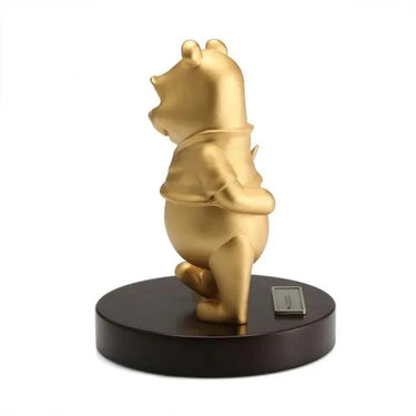 Gold bear figurine on a dark base with a white background