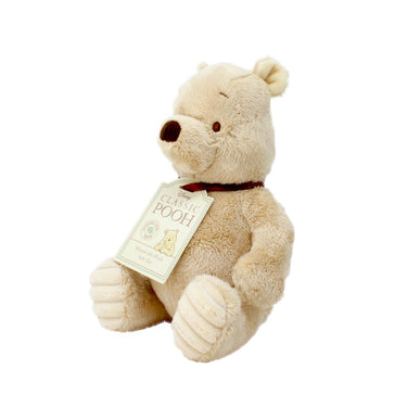 A plush toy depicting the character Winnie the Pooh from the Hundred Acre Wood stories, sitting upright with a tag attached to its neck.