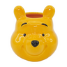 A ceramic mini pot shaped like Winnie the Pooh bear, primarily yellow in color with facial features and a smile depicted.